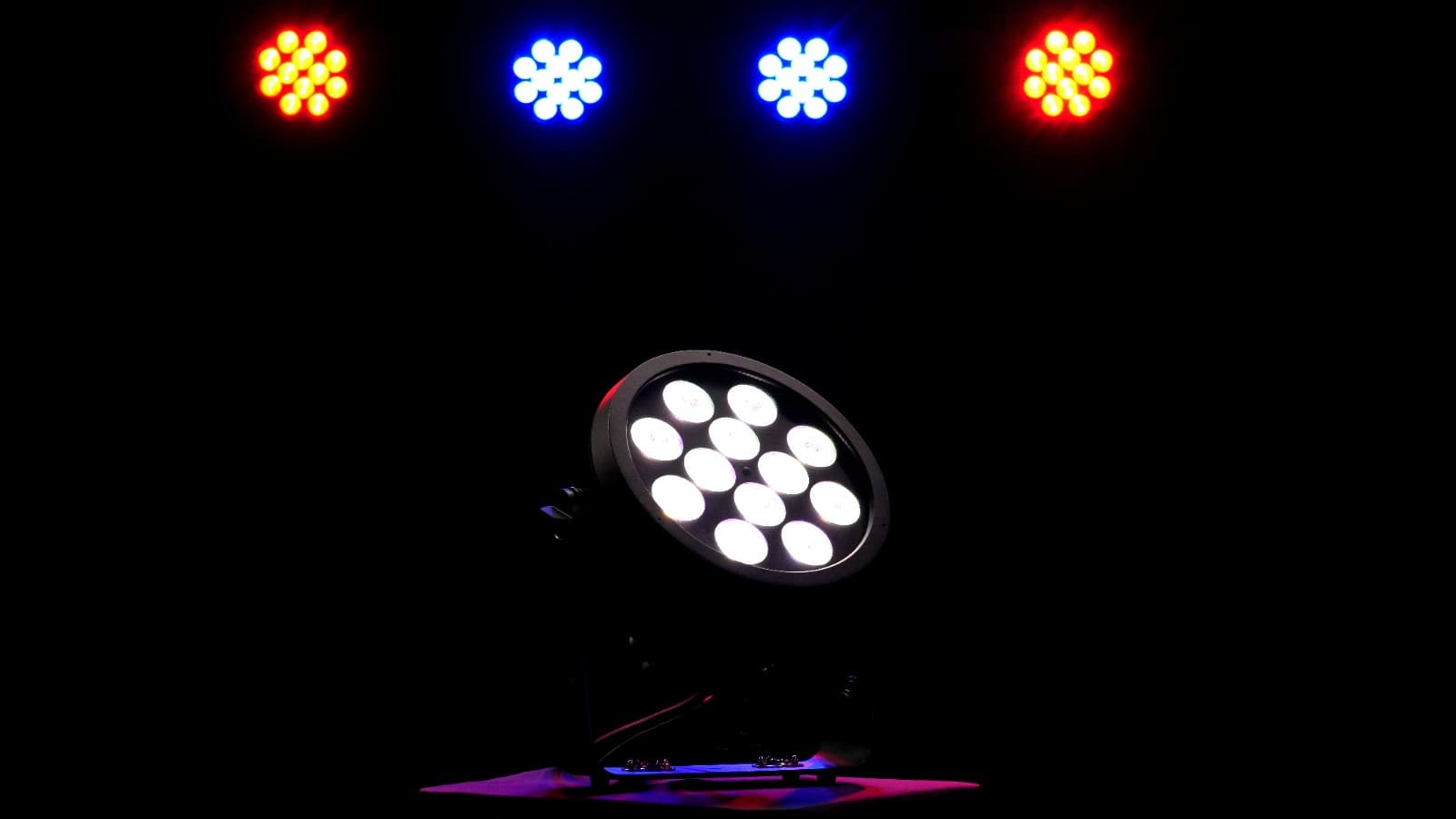 Rodie X12 RGBACL LED wash light glowing white on stage beneath red and blue wash fixtures