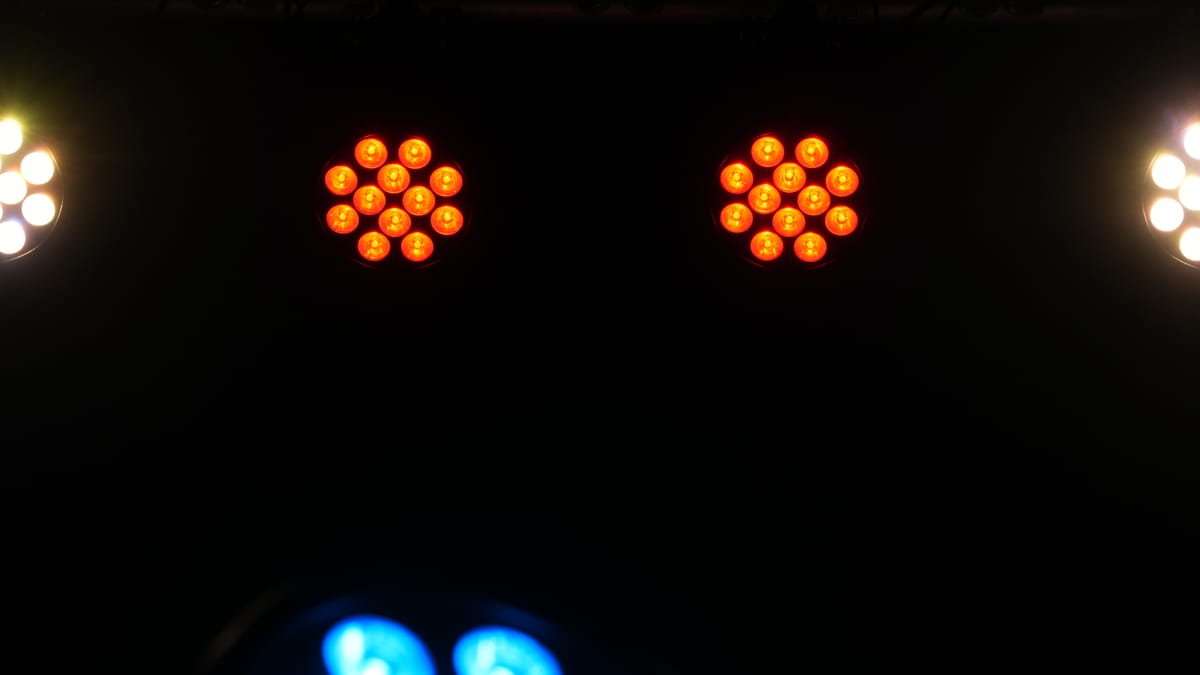 Two Rodie X12 wash lights glowing amber on a dark stage, showing all 12 six-color LEDs